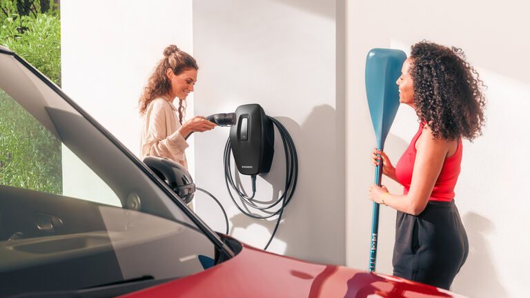 Eine Frau lädt ihr Elektroauto an einer MENNEKES-Wallbox